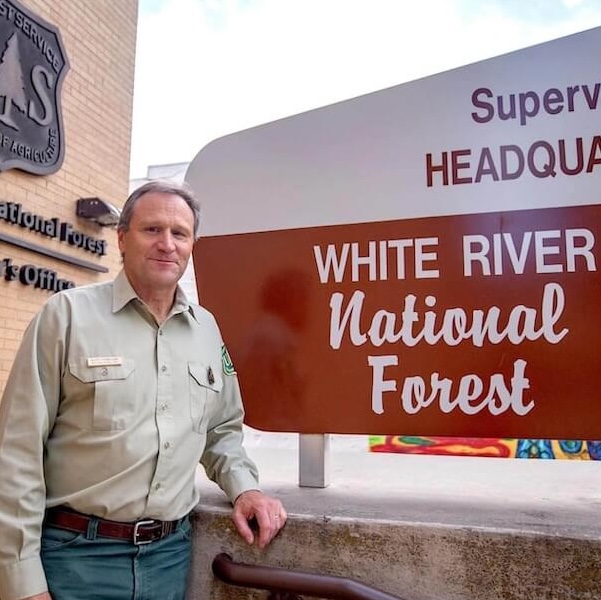 Scott Fitzwilliams stands in front of the White River National Forest Supervisor's Headquarters sign